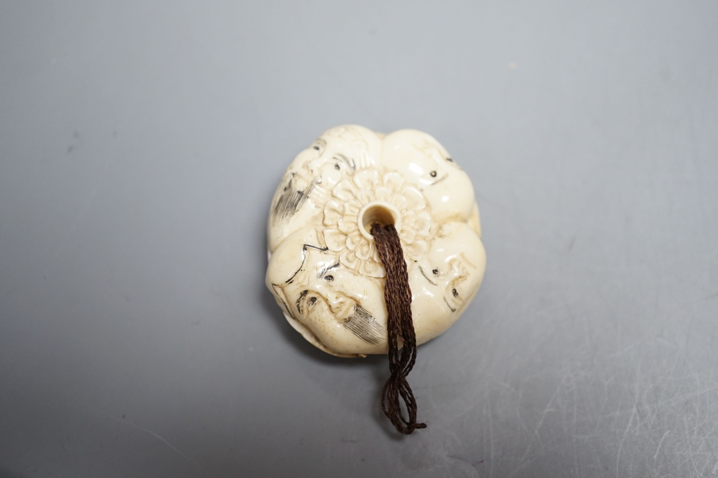 A Japanese ivory netsuke of a man reading a book, a small okimono of Guanyin and monkeys, a Manju netsuke of masks and an early 20th century netsuke of a bearded man
